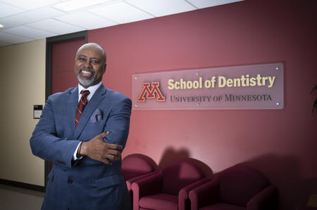 Keith A Mays, DDS, MS, PhD and Dean of Minnesota School of Dentistry wears blue suit in front of School of Dentistry sign