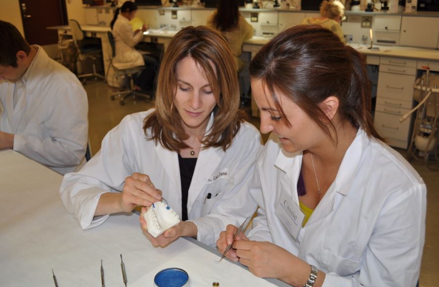 School of Dentistry faculty showing a dental mold to a student