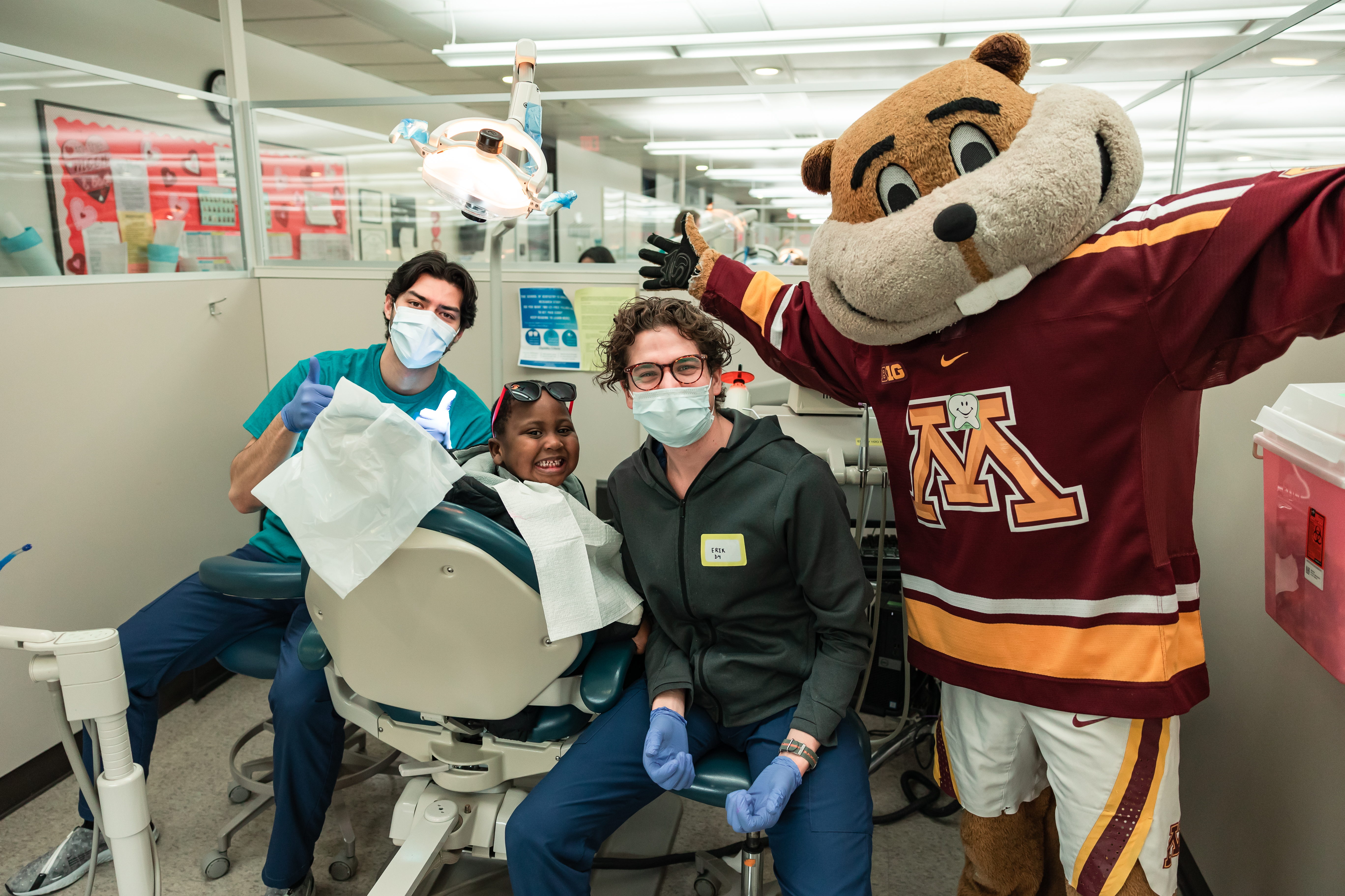 Two students and a child patient pose with Goldy