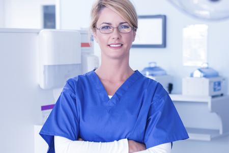woman wearing scrubs and glasses folding arms in dental office
