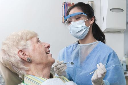 young female dentist speaks with senior female patient
