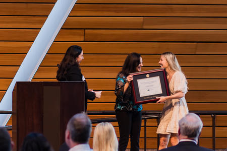 A DDS student receives an award from two faculty on stage