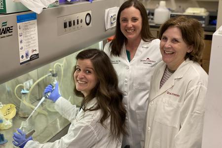 Rachel Phillips, Amy Tasca and Kim Mansky smile while working in a research lab