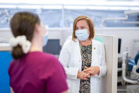 Yvette Reibel, masked, talks with a dental hygiene student in the pre-clinic