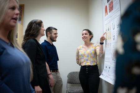 Flavia Saavedra presents a poster to other students