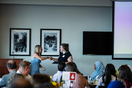 Aricka Tusha shakes hands with Cyndee Stull as she receives her award
