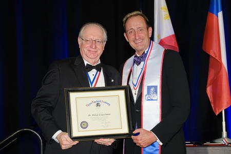 Two men holding award at induction ceremony.
