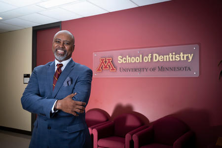 Dean Keith A Mays DDS MS PHD in front of a logo of the School of Dentistry