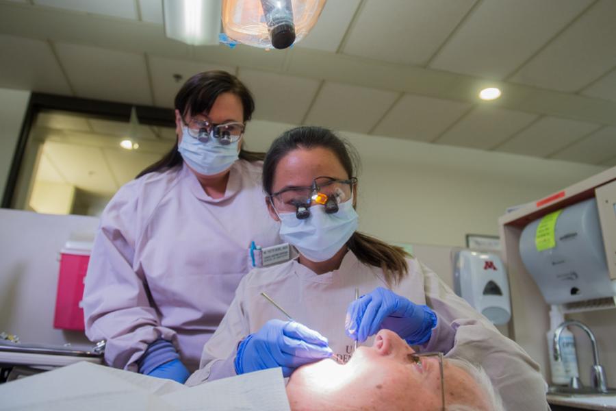 Female Dental Hygiene student works on patient while instructor watches