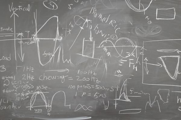 graphs, notes, and equations written on chalkboard