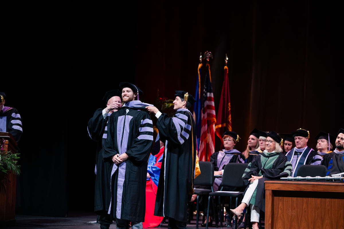 A graduate is hooded onstage