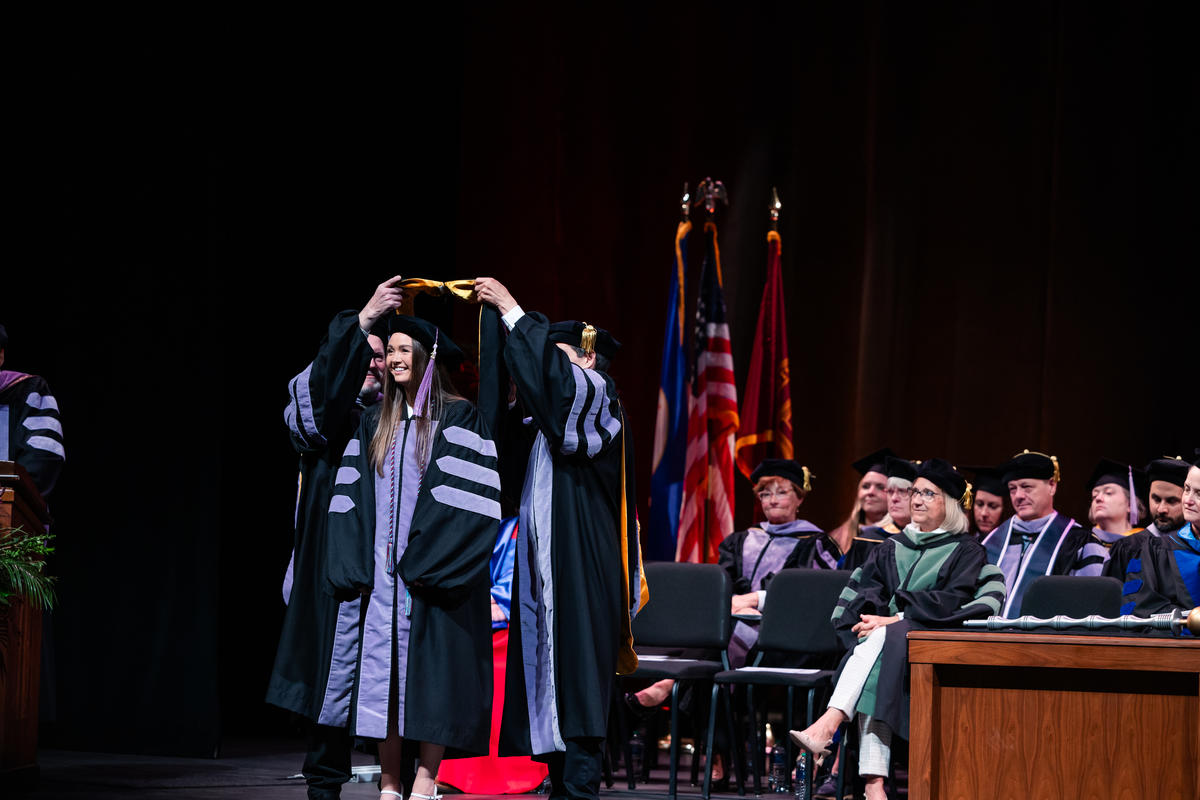 A graduate is hooded onstage