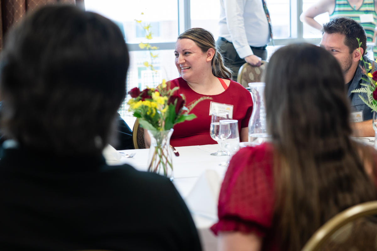 Student smiles and talks with other students at banquet table