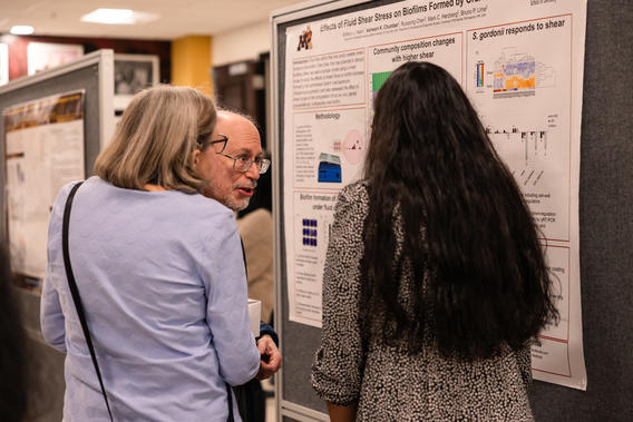 Attendees listen to a researcher explain her poster