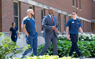 Jose Gigato Gonzales, Dean Keith Mays and a student walk by Moos Tower