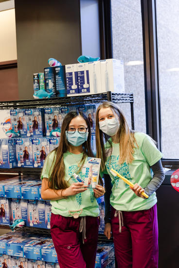 Two students pose with toothbrushes and supplies at Give Kids a Smile day