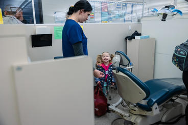 A child  smiles at a provider next to the dental chair