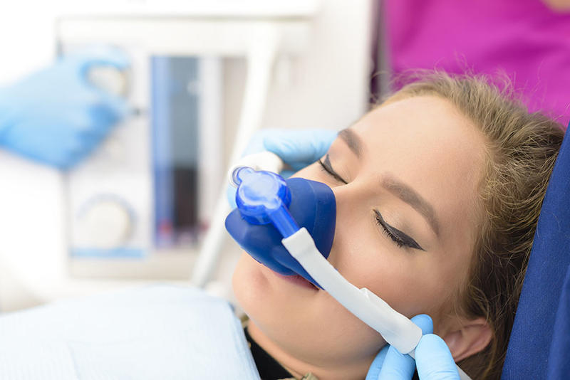 female patient with nitrous mask on, appearing to be asleep in dental chair