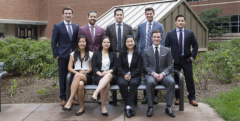 Prothodontics students posing in professional dress on a bench outside