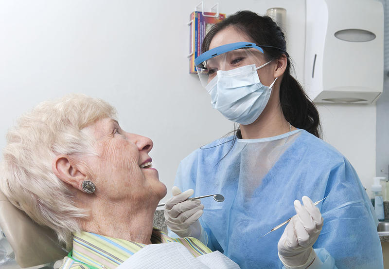 young female dentist speaks with senior female patient