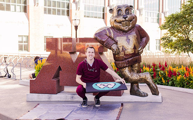 Tim Bitner poses with his rice creation in front of Goldy Gopher