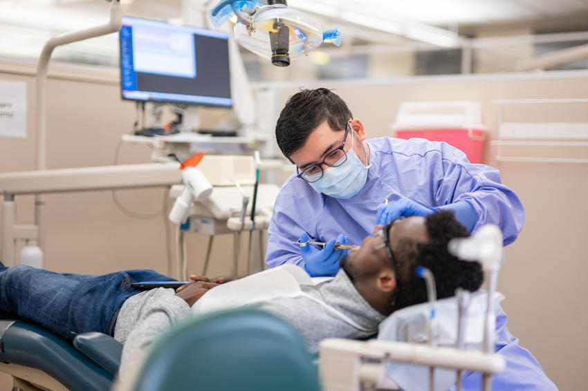 A dental student performs a deep cleaning on a periodontology patient