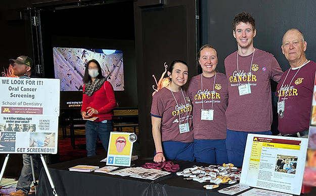 Three students and Nelson Rhodus pose at the Goldy vs. Cancer booth
