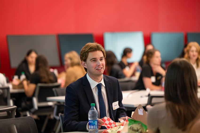 a young man in a suit and a name tag at orientation lunch