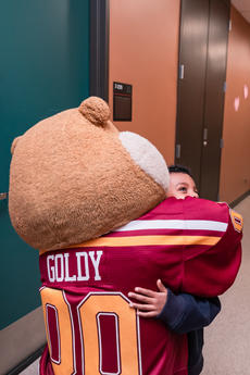 A child hugs Goldy in the hallway