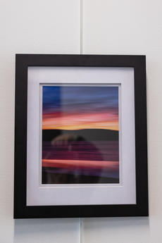 Photograph of a sunset, with vibrant reds, pinks, oranges, and blues, in blurred, paint-like lines