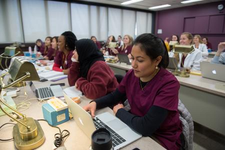 Students in classroom lecture wearing maroon scrubs