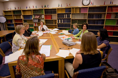 people meeting at a large table in a library