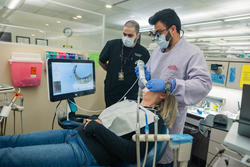 A student performs a digital scan while an instructor looks on