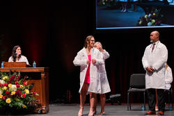 A student smiles as she dons her white coat
