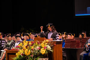 Anderson raises hand and smiles at commencement