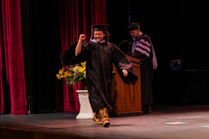 Pedro Lopez Vega smiles and raises his hand in a cheer as he crosses the stage
